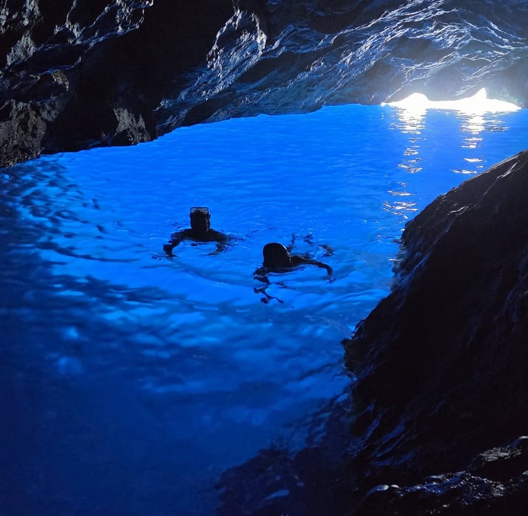 Couple nageant dans une eau bleue azur a l'intérieur d'une grotte marine.