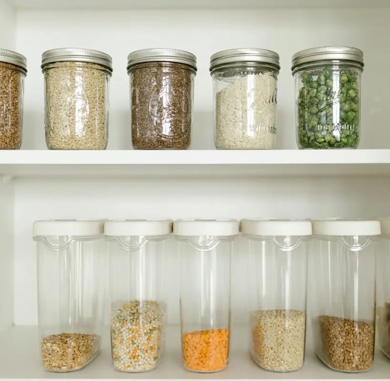 Organized kitchen pantry featuring glass mason jars and clear airtight containers filled with bulk dry goods.