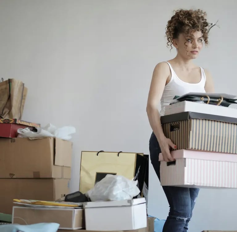A woman carrying a stack of decorative boxes while moving into a new apartment.