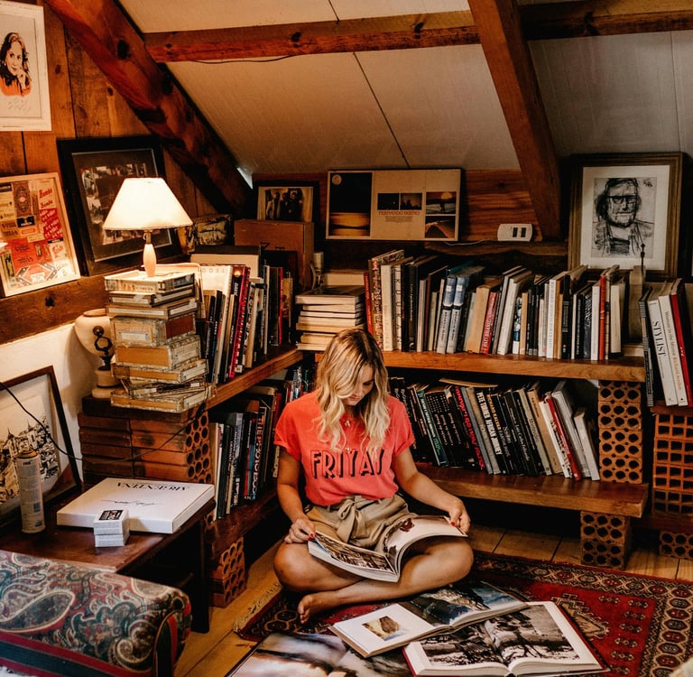 Young woman in attic, with bookshelves, reading a book