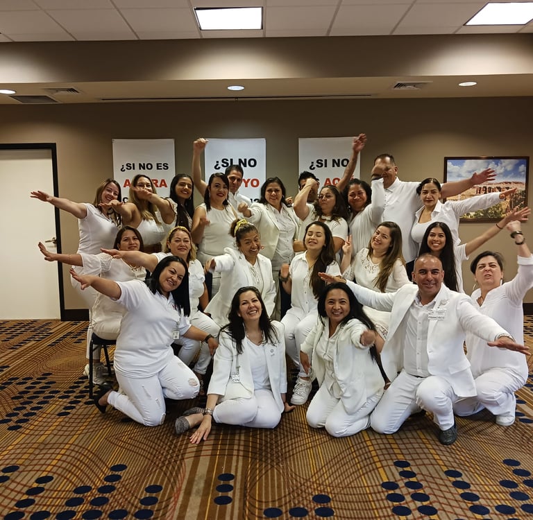 A diverse group of community volunteers posing together outdoors in white and green attire.