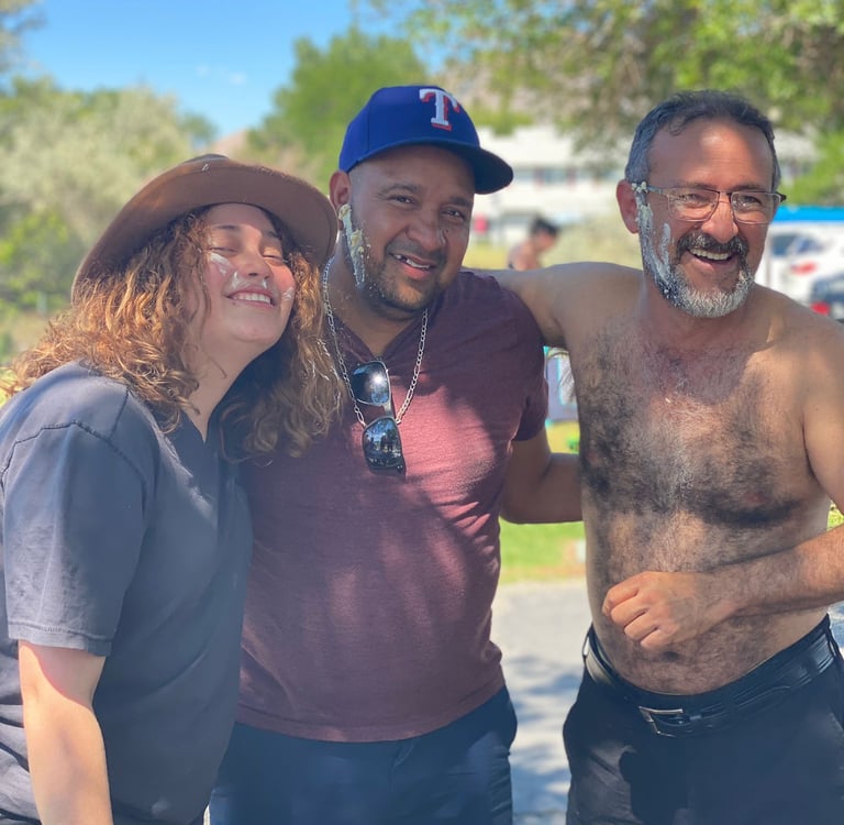 A group of happy friends smiling outdoors with cake frosting on their faces during a summer celebration.