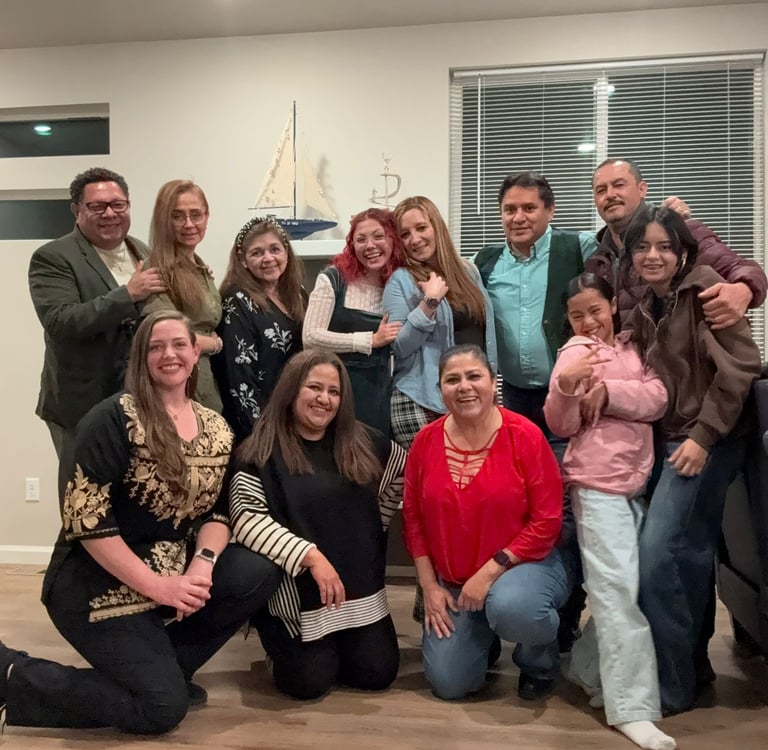 A diverse multi-generational family posing together for a group photo in a living room.