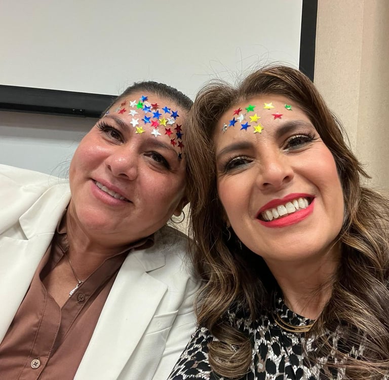 Two smiling women with colorful star stickers on their foreheads posing for a close-up portrait.