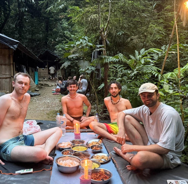 Friends enjoying a traditional dinner by candlelight at a jungle retreat base camp.
