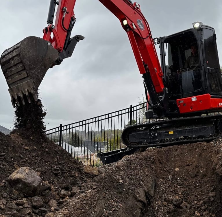 Kubota excavator digging dirt in residential backyard