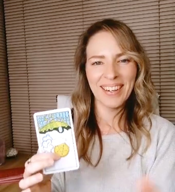 Natalie holding the Ace of Pentacles reversed during a live tarot reading.