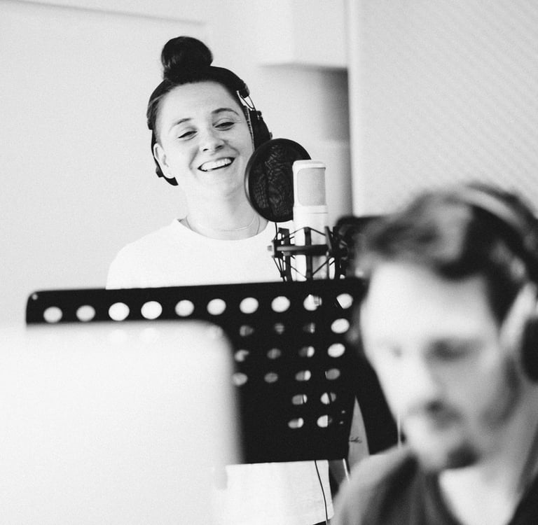 Female vocalist recording in studio booth during vocal session