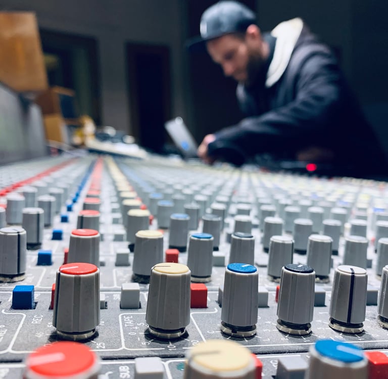 Mixing console close-up with producer working in blurred background