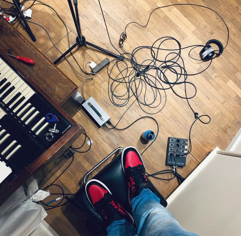 Studio floor with cables, Hammond keys and red sneakers visible
