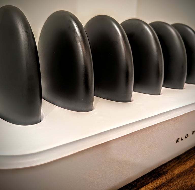 Elo Plus hot stone massage set with black basalt stones in a white warming station charger.