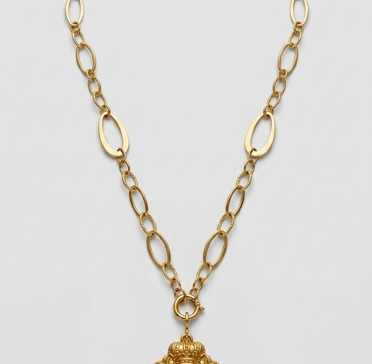 Gold chain necklace featuring a vintage crowned heart pendant with a white stone center.
