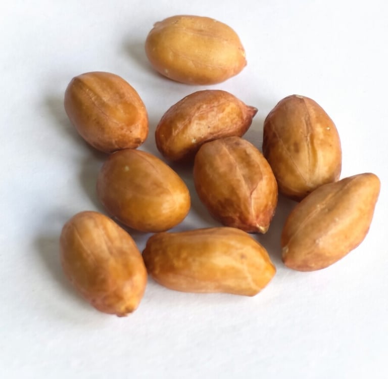 A small cluster of raw shelled peanuts scattered on a plain white surface.