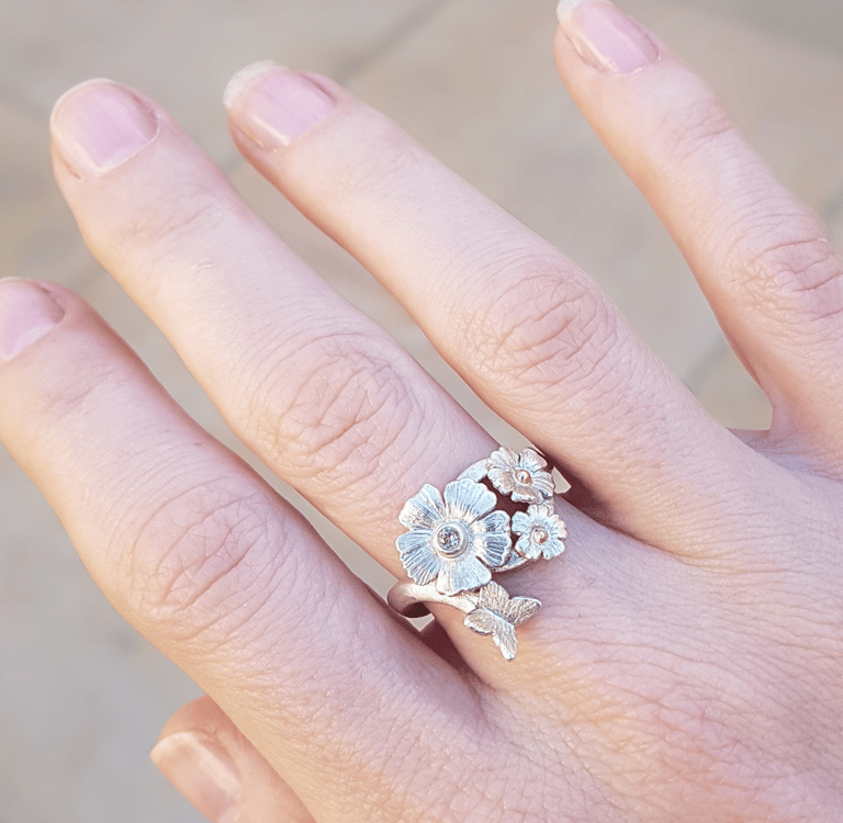 a woman's hand holding a ring with flowers