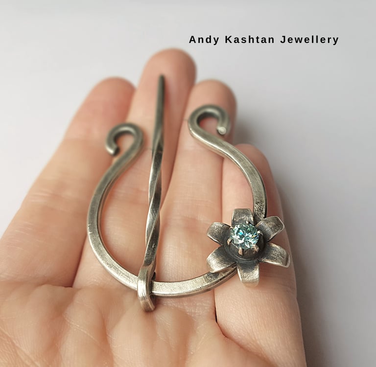 Handmade sterling silver penannular brooch featuring a gemstone flower detail for scarves and shawls.