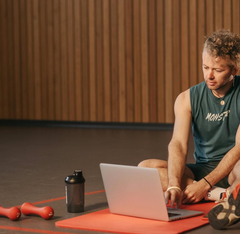 a man sitting on a mat with a laptop