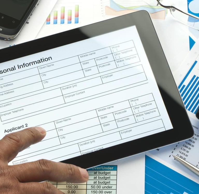 A tablet displaying a form labeled "Personal Information" amidst business documents, charts, and a smartphone.