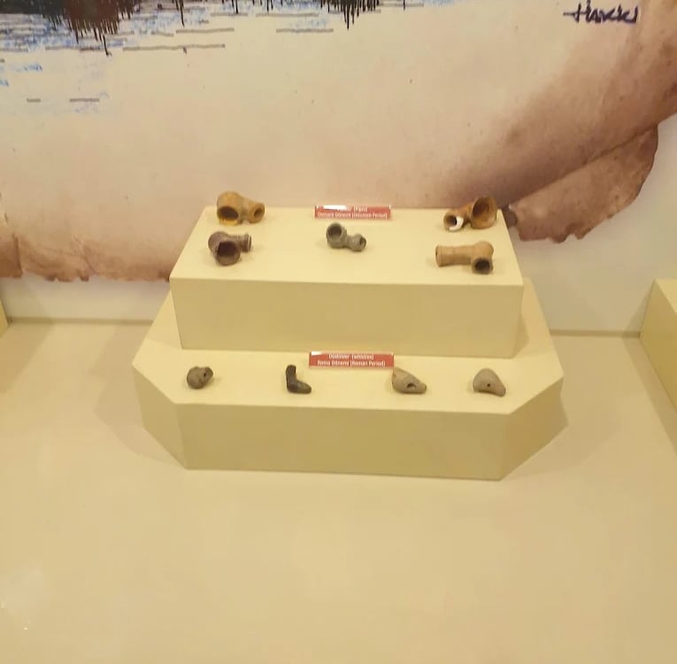 Ancient Roman and Ottoman period clay pipes and artifacts on display at a museum.