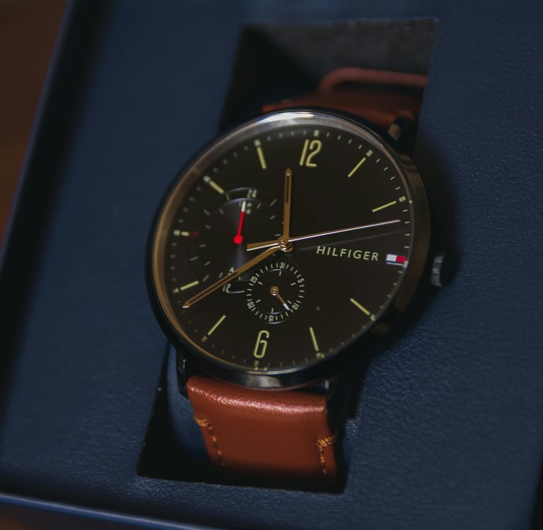 A luxury Tommy Hilfiger men's analog watch with a black dial and brown leather strap in a gift box.
