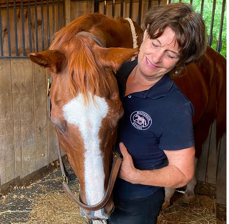 Calm, relaxed horse with eyes closed, resting his head on Danna's shoulder during bodywork session.