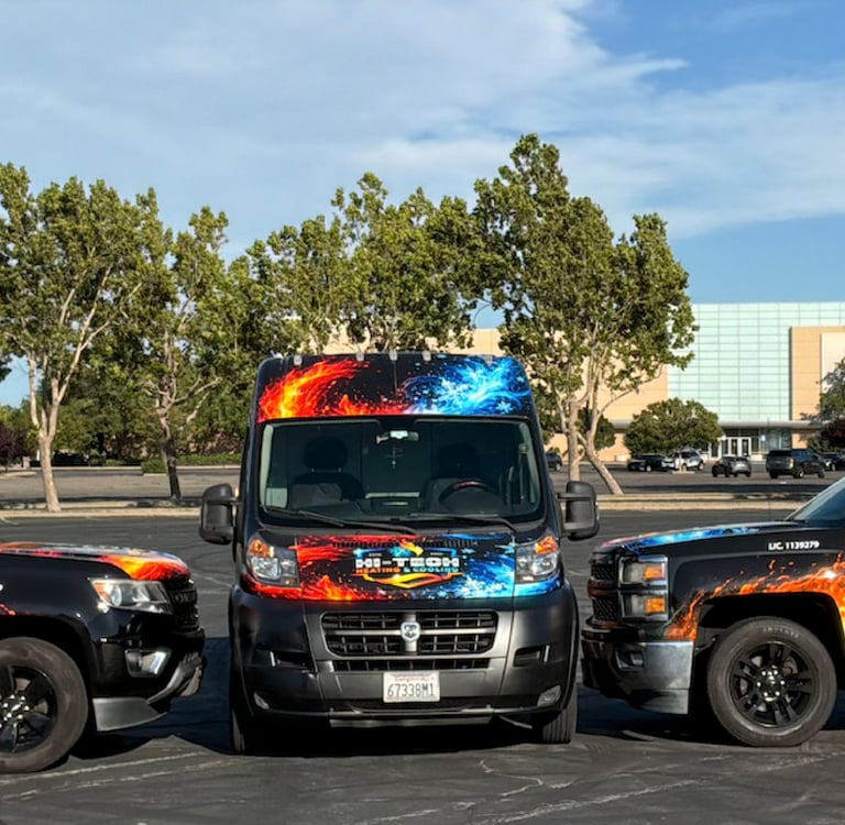 A fleet of Hi-Tech Heating and Cooling HVAC service trucks and vans with custom fire and ice wraps parked in a lot.