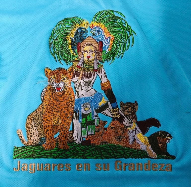 Aztec warrior embroidery with jaguar on a blue jersey featuring Jaguares en su Grandeza text.