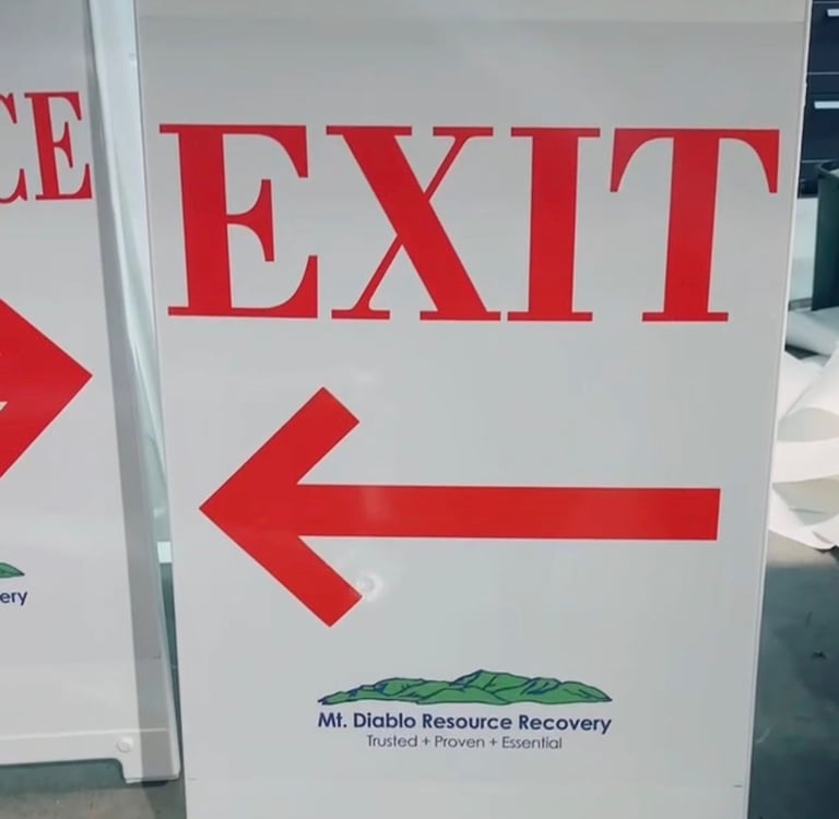 White plastic A-frame sign with red Exit text and arrow for Mt. Diablo Resource Recovery facility.