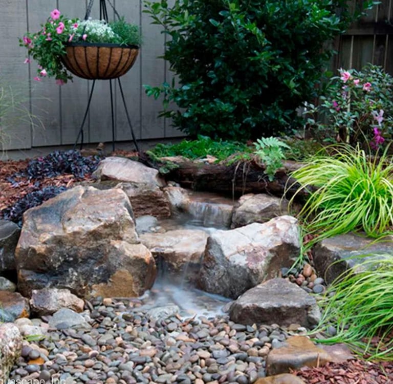 Backyard garden waterfall surrounded by rocks and plants