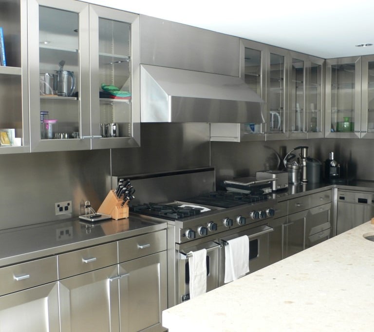 stainless steel kitchen with open shelving, glass doors, countertop and backsplash