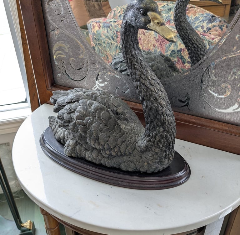 a swan - shaped sculpture of a swan with a mirror in the background
