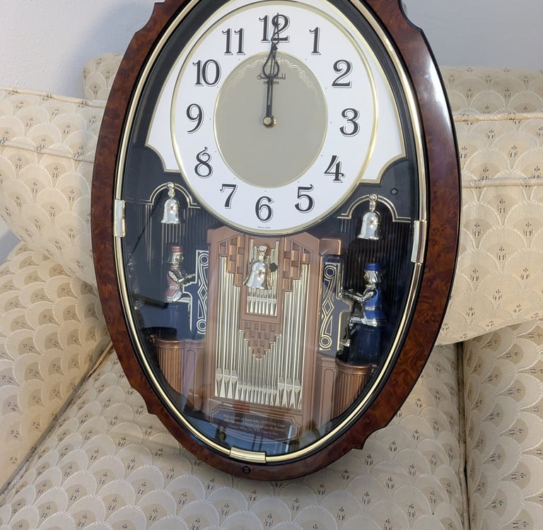Vintage Small World Rhythm musical wall clock with wood grain frame and rotating pendulum figures.