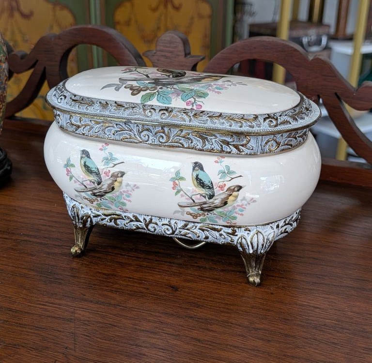 Vintage ceramic jewelry box with floral bird illustrations and ornate gold filigree trim.