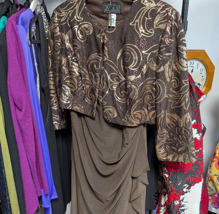Elegant two-piece brown dress with a gold sequined floral bolero jacket hanging on a clothing rack.