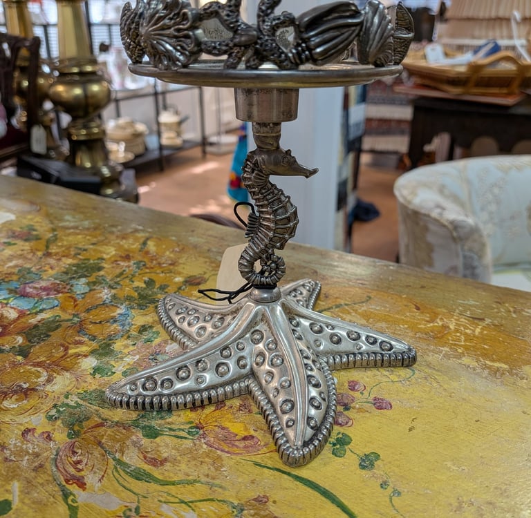 Vintage coastal candle holder with a seahorse stem and starfish base on a floral table.