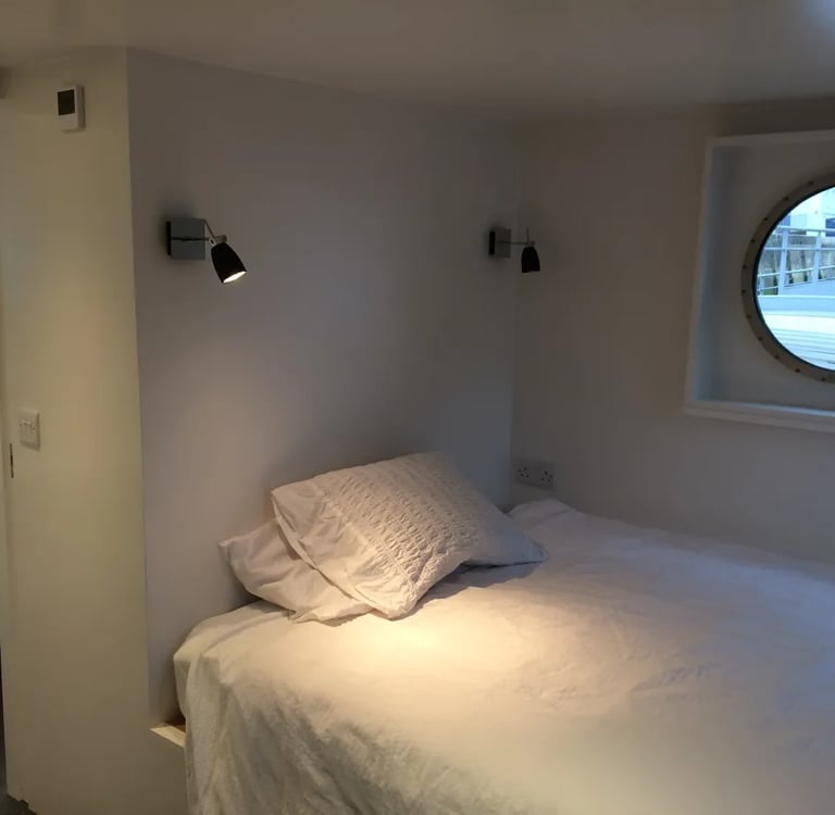 Une chambre sur peniche avec un hublot