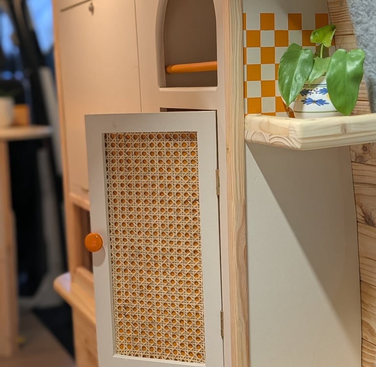 Détail mobilier de van en bois avec porte en cannage et crédence damier orange, style bohème et chal