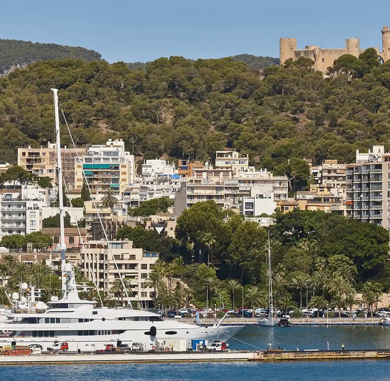 Vista de Palma con puerto, edificios residenciales y el castillo de Bellver al fondo