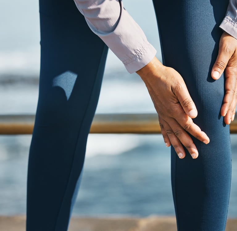 A runner holding their injured knee outdoors, highlighting sports-related joint pain and recovery.