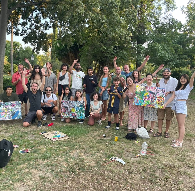 Des amis souriants tiennent des tableaux abstraits lors d’un événement artistique dans un parc
