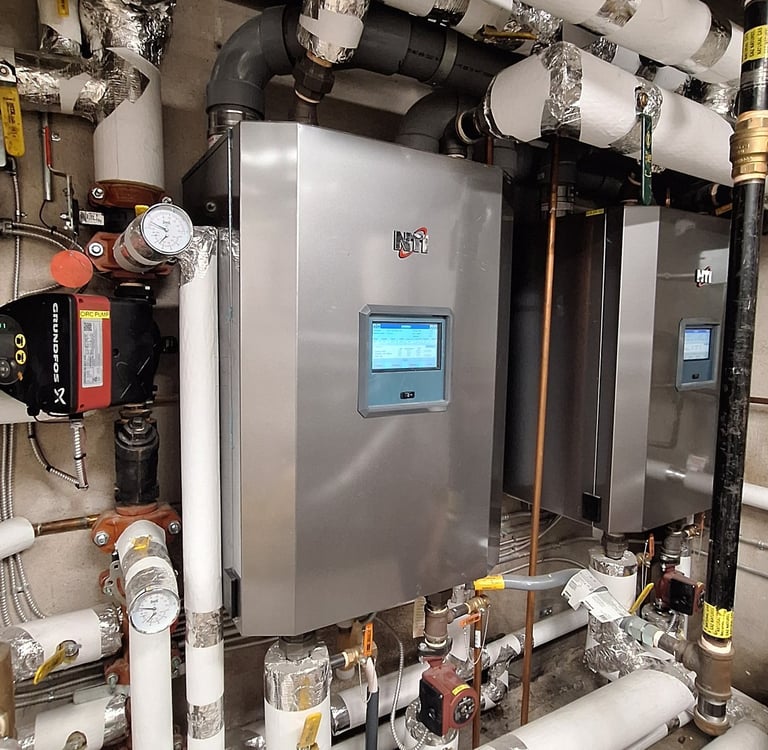 Commercial high-efficiency NTI gas boilers with insulated pipes and digital controls in a utility room.
