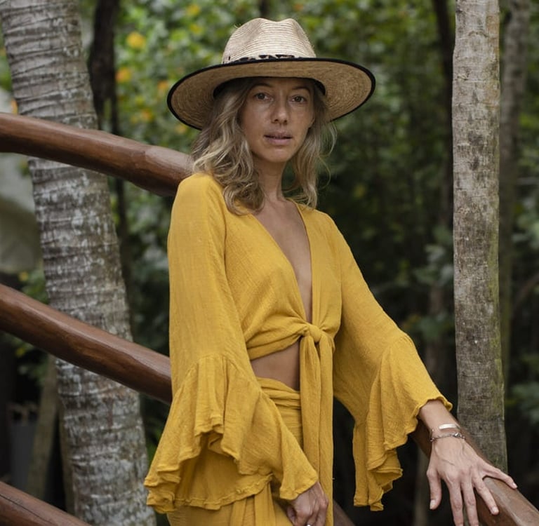 mujer usando un vestido amarillo boho chic Tulum y sombrero. con fondo en la selva