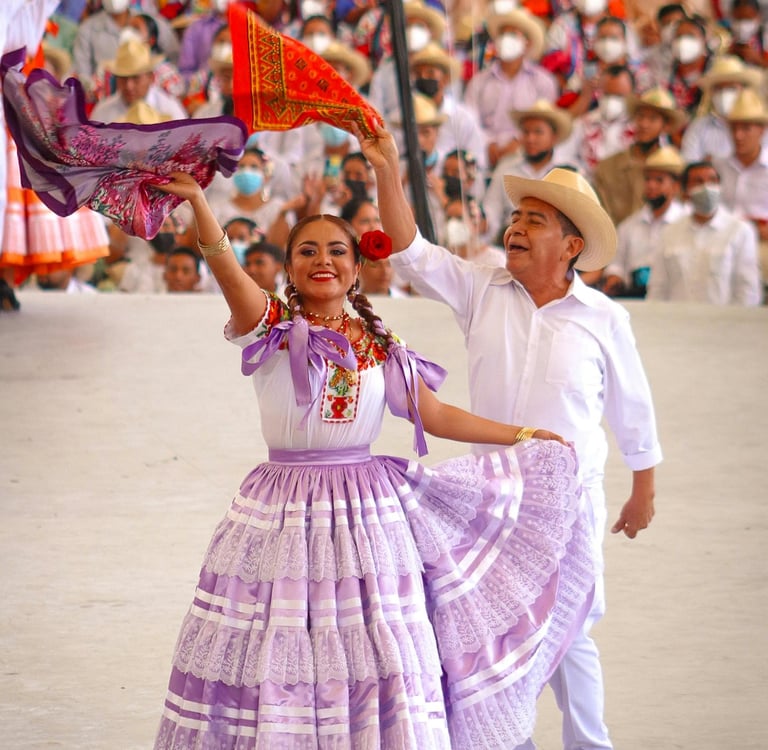 Pareja bailando danza folclórica mexicana en la Guelaguetza, Oaxaca, con trajes regionales