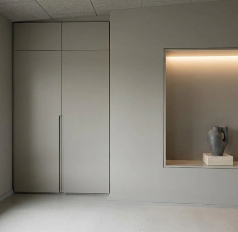 Camera minimalista con armadiatura a tutta altezza e nicchia illuminata a parete