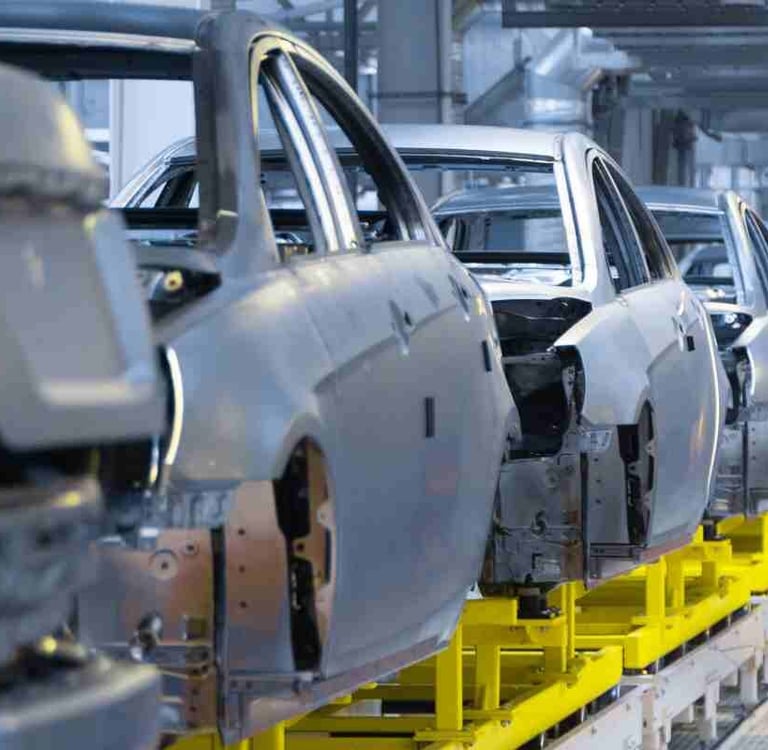 Automotive assembly line showing car body frames on a conveyor belt in a modern manufacturing plant.