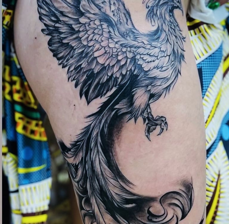 Black and grey phoenix tattoo on upper thigh, professional tattoo studio in Hurghada”