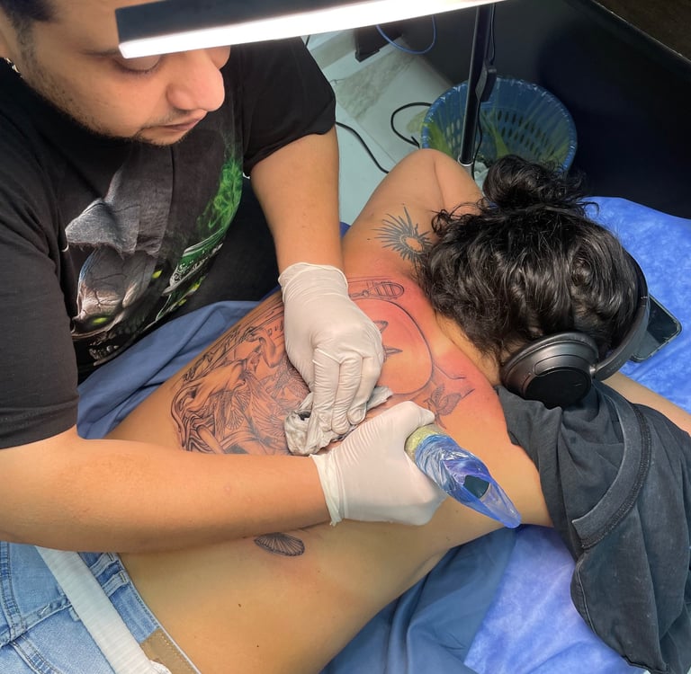 Tattoo artist working on a large back tattoo in a Hurghada tattoo studio 