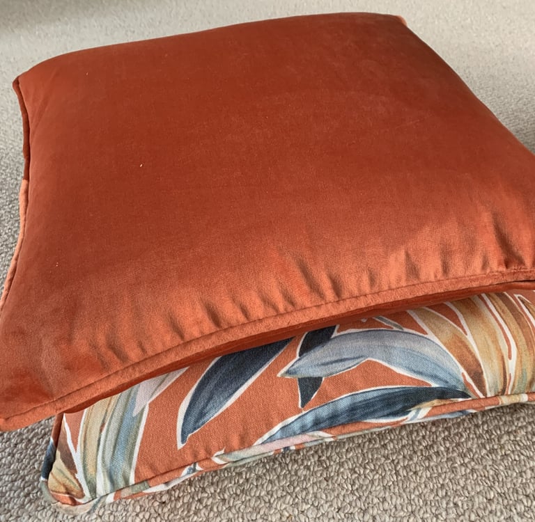 2 coordinated piped cushions with dominant colour in burnt orange