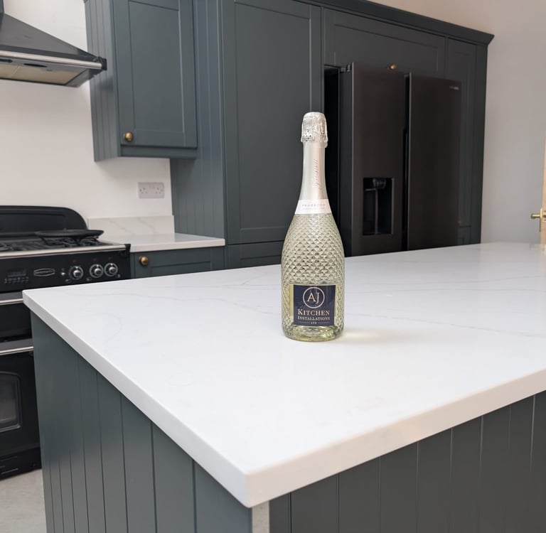 white countertop, dark green/light grey cupboard and champagne on top