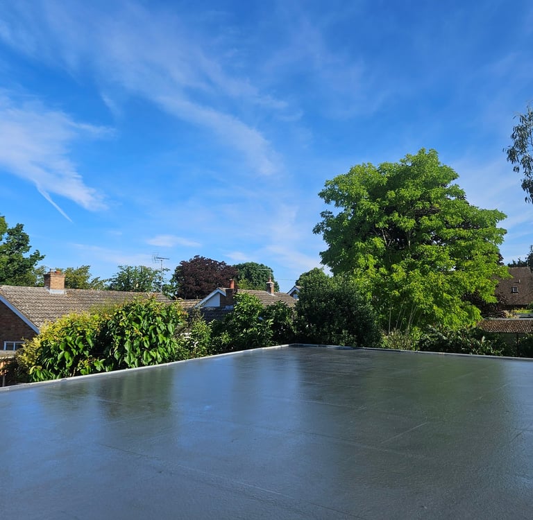 Modern grey flat roof installation with a smooth waterproof finish under a blue sky.