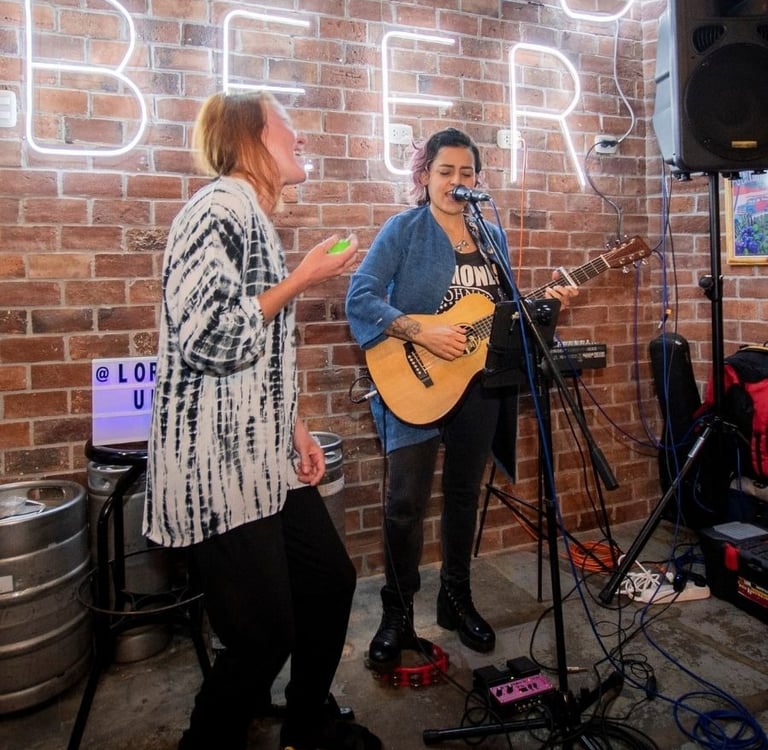 Lorena Uría cantando con su loopera en un bar en Miraflores invitando a una turista a participar